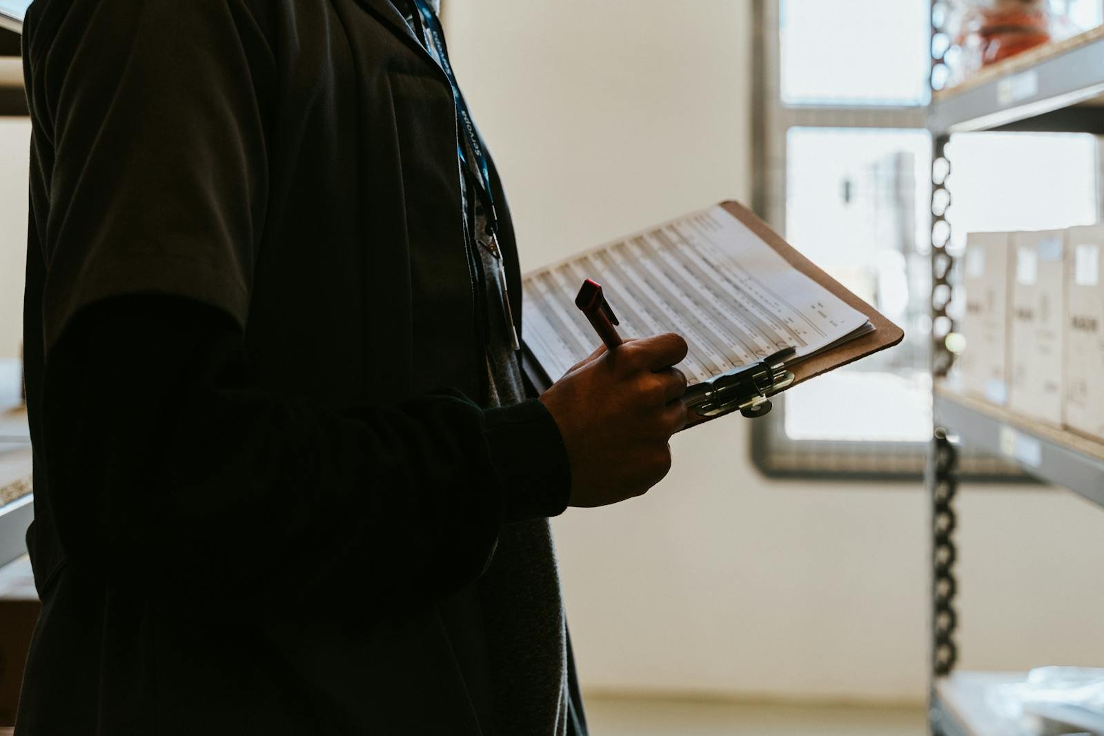 Industrial worker managing inventory in a warehouse with a clipboard and checklist.